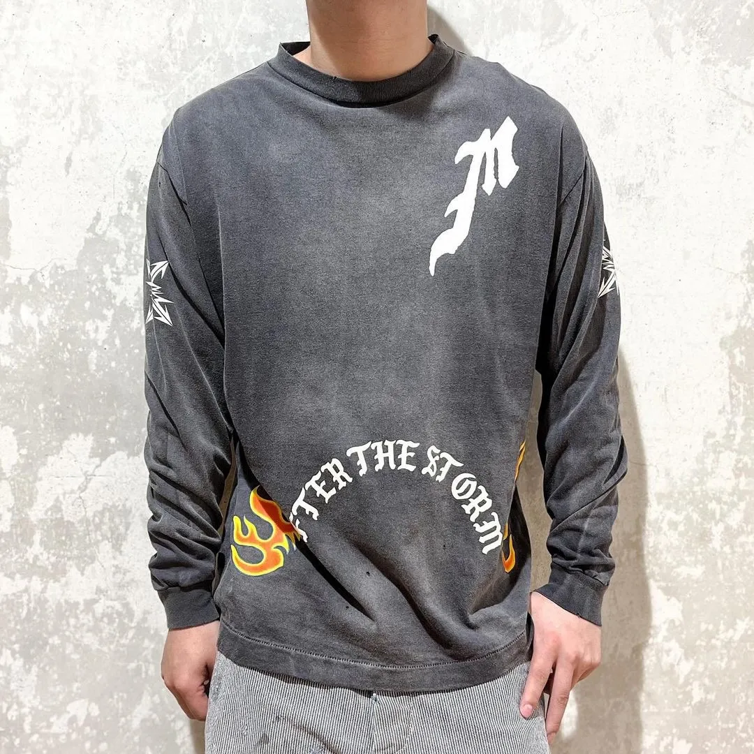 SAINT Mxxxxxx M/AFTER LS_TEE/BLACK Flame arrow Letter M retro distressed long tee Washed black S-XL Tubular fabric Assute ready-made garments dyed The whole piece is sprayed with horse-hair spray and then sprayed again to fade the color. The collar and cuffs are frayed. Many places are frayed. Extra large printing position. Very difficult to print. Complete accessories. With little angel anti-counterfeiting label.